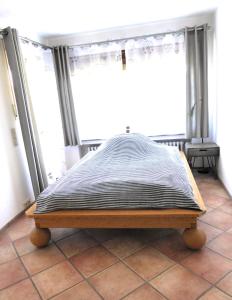 a bed sitting on a tiled floor in a room with windows at Wohlfühlen in Wiehl - Drabenderhöhe in Wiehl