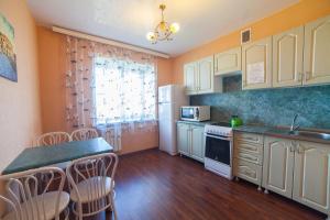 cocina con armarios blancos, mesa y sillas en Apartments KSGM London at Gamarnika 6A, en Khabarovsk