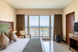 a hotel room with a bed and a large window at Barceló Mussanah Resort, Sultanate of Oman in Mussanah