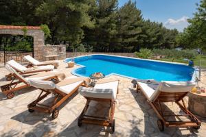 a group of lounge chairs next to a swimming pool at Villa Zlatni Rat with pool by the beach Zlatni rat in Bol - Brac in Bol