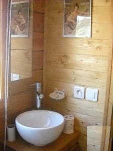 baño con lavabo blanco en una pared de madera en Aurel inattendu en Aurel