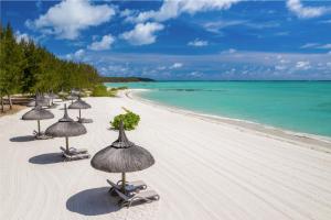 um grupo de guarda-sóis de palha numa praia em Four Seasons Resort Mauritius at Anahita em Beau Champ