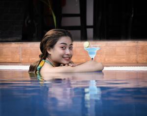 una joven con un cóctel en una piscina en Golden Orchid Angkor, en Siem Reap