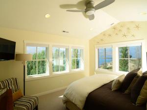 a bedroom with a bed with a ceiling fan and windows at Arroyo #60 in Chelan