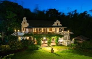 a large white house with a garden at night at Ataalaya Farmhouse in Batangas City