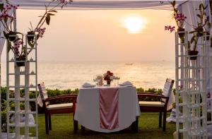 a white table with a white chair next to a body of water at Katathani Phuket Beach Resort - SHA Extra Plus in Kata Beach