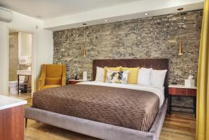 a bedroom with a large bed and a stone wall at Hotel Manoir D'Auteuil in Quebec City