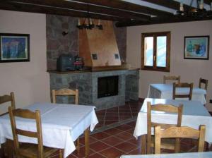 a dining room with two tables and a fireplace at Casa Feixas in Gistaín