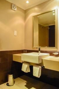 een badkamer met een wastafel, een spiegel en handdoeken bij Cresta Mahalapye Hotel in Mahalapye
