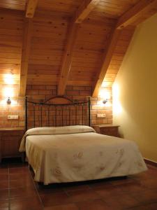 a bed in a room with a wooden ceiling at Casa Feixas in Gistaín