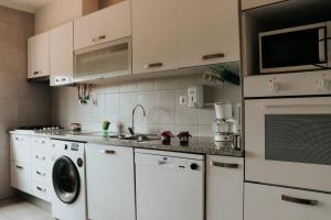 a kitchen with white cabinets and a washer and dryer at Sublime Sun & Van - By Meco Stays in Alfarim