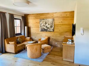 a living room with wooden walls and a couch and chairs at Appartements Oswaldeck in Bad Kleinkirchheim