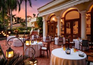 un restaurante con mesas y sillas blancas y palmeras en Casa Velas Adults Only All Inclusive, en Puerto Vallarta