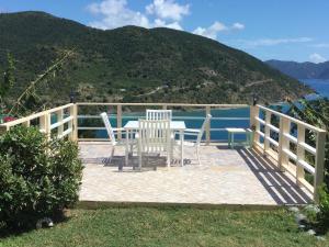 a table and chairs on a deck with the view of the water at Ocean View Villas in Jost Van Dyke