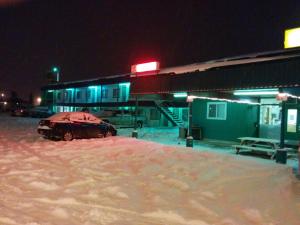een auto geparkeerd voor een benzinestation in de sneeuw bij Shamrock Motel in Valleyview
