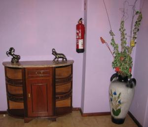 Zimmer mit einem Feuerlöscher und einer Vase mit Blumen in der Unterkunft Moledo Beach - Guest Apartment in Moledo