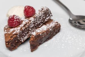 a white plate with a piece of chocolate cake and two raspberries at The Lawrence in Burnley