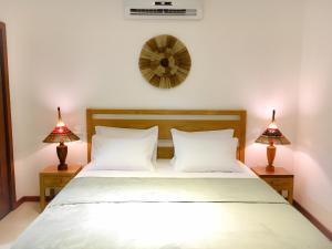 a bedroom with a bed with two lamps and a clock at Carapitangui Pousada in Barra Grande