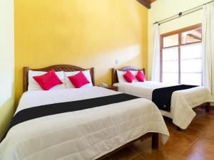 - une chambre avec 2 lits dotés d'oreillers rouges et noirs dans l'établissement Hotel Jardín de Tereza, à Comitán de Domínguez