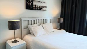 een slaapkamer met een wit bed en 2 lampen bij 19 Brussels Expo in Wemmel