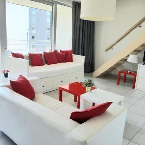 uma sala de estar com 2 sofás brancos e almofadas vermelhas em 19 Brussels Expo em Wemmel