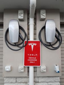 um sinal num posto de gasolina com um sinal Tesla em Sport Of Kings Motel em Rotorua