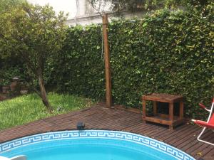 a pool with a table and a chair next to a hedge at B&B Polo in Buenos Aires