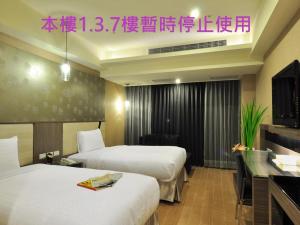 ein Hotelzimmer mit 2 Betten und einem TV in der Unterkunft Goodness Plaza Hotel in Taishan