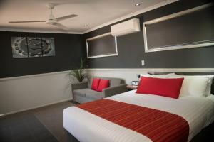 una camera da letto con un grande letto con cuscini rossi di The Rocks Motel a Charleville