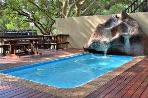 a swimming pool with a waterfall in the middle of a deck at Bushriver Lodge in Mica