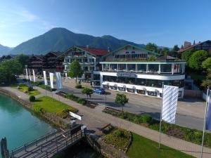 un edificio junto a un río con montañas en el fondo en Hotel Bachmair am See, en Rottach-Egern