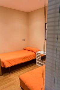 2 Betten in einem kleinen Zimmer mit orangefarbener Bettwäsche in der Unterkunft Paseo Butrón by Basquelidays in Hondarribia