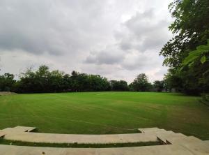 a large green field with trees in the background at The Gateway Resort Damdama Lake in Gurgaon