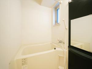 HIT Tenjin في فوكوكا: حمام أبيض مع حوض استحمام ونافذة