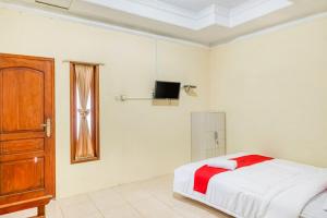 a bedroom with a bed and a tv on the wall at RedDoorz near Wisata Pantai Parangtritis in Kretek