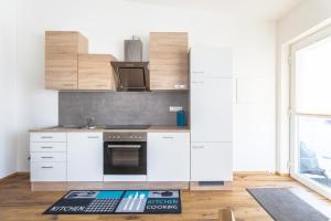 a kitchen with white cabinets and a stove top oven at Alpen-Hostel - Apartment Morgen- und Abendsonne mit Motorradvermietung in Memmingen