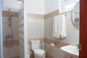 Un baño con inodoro, lavabo y espejo. en Coliseum Studios & Apartments, en Pefki 19 fotos más