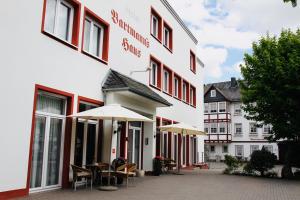 a building with tables and umbrellas in front of it at Hotel Bartmanns Haus in Dillenburg