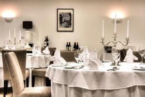 a dining room with tables with white tablecloths at Hotel Bartmanns Haus in Dillenburg