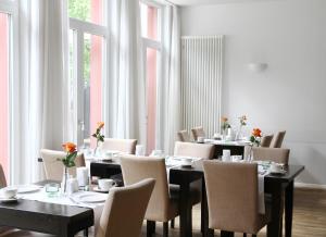 a dining room with tables and chairs and windows at Bartmanns Haus & Schwan GmbH in Dillenburg
