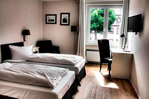 a hotel room with two beds and a desk and a window at Hotel Bartmanns Haus in Dillenburg