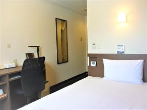 a bedroom with a bed and a desk and a chair at Smile Hotel Mito in Mito