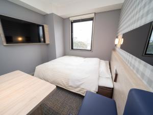 a small room with a bed and a tv at Super Hotel Anan City Hall Smoke-Free in Anan