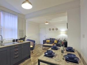 a kitchen and living room with a table with dishes on it at Lake View Apartments, Oulton Broad in Lowestoft