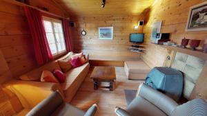 Cabaña de madera con sala de estar con sofá y TV. en Bergestille, en Blatten bei Naters