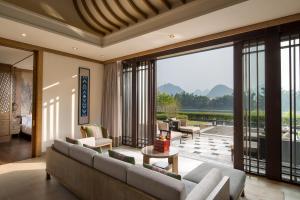 a living room with a couch and a large window at Banyan Tree Yangshuo in Yangshuo
