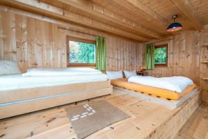 two beds in a room with wooden walls at Forest Chalet Resort FELIZITAS in San Felice