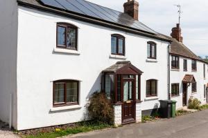 a white house with brown windows and a street at Herefordshire Holiday Cottages in Lea