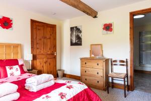 a bedroom with a red bed and a wooden dresser at Herefordshire Holiday Cottages in Lea +38 photos