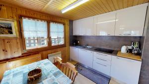 a kitchen with white cabinets and a table at Gustav GS2 in Blatten bei Naters